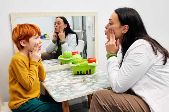 Speech therapy. Therapist shaping a boy's mouth in order for his to make correct sound