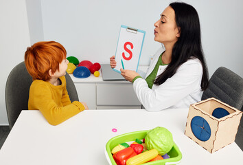 Speech and language therapy for children. Handsome boy patient pronouncing letter S with speech pathologist in speech therapist's office
