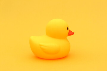 A yellow rubber duck stands on a yellow background.