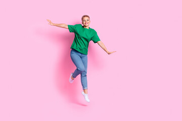 Full size photo of gorgeous adorable pleasant girl dressed green t-shirt flying holding palms like wings isolated on pink color background