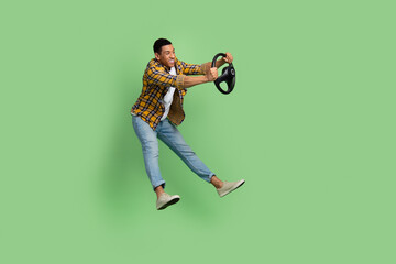 Full body profile portrait of carefree cheerful man jump hold wheel empty space isolated on green color background