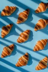 Pattern of croissants with shadows on a blue background. Food concept.