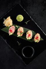 Elegant spicy sushi assortment with salmon, shrimp, tuna, and eel, top view on dark slate