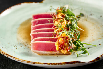 Seared tuna tataki with mango salsa and ponzu sauce on a speckled ceramic plate