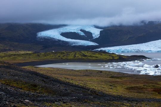 Heart shaped glacier outlet with a glacier lagoon surrounded by greenery in Iceland