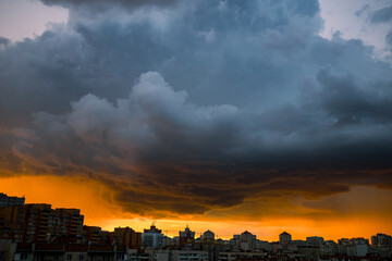 Wide angle shot of dramatic stormy sunset sky with clouds over city skyline background. - 737384477
