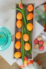 Happy Easter, Stylish Easter eggs in wooden plate, tulips and linen napkin on rustic white table