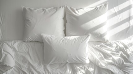 a bed with a white comforter and four white pillows and a white headboard with a white wall in the background.