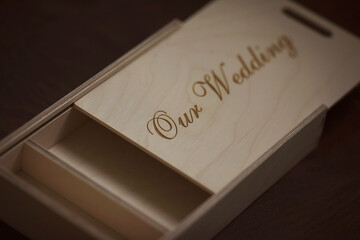 Wooden photo box for photo storage on wooden background. Box with flash with laser engraving "our wedding" set for the photographer, presentable set of photos, luxury feedback to client.