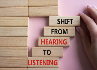 Listening symbol. Wooden blocks with words Shift from Hearing to Listening. Businessman hand....