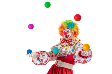 Funny clown juggler. Entertainer professional actor in colorful suit and wig juggling with colorful balls. Joker jester, pantomime, mime with clown whiteface makeup at event, kids party, circus