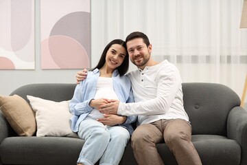 Obraz premium Portrait of happy pregnant woman with her husband on sofa at home
