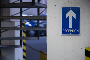 Blue and white sign with white arrow directing vistor, guest, employee to reception. Clear signage.