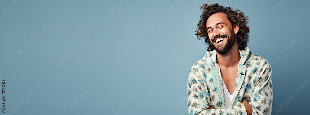 Wall mural Smiling man in pajamas on a blue background. Free space for product placement or advertising text.