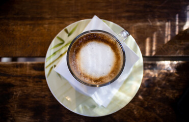 a cup of cappuccino on the wooden table, isolated and top view