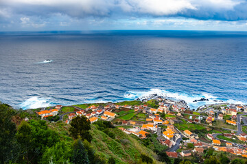 View of the village of Porto Moniz with volcanic lava pool, Atlantic ocean and green forest. Madeira Island, Portugal