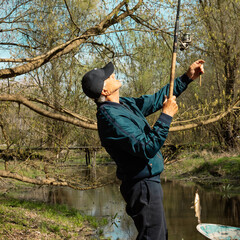 Fishing on the river.
Side portrait of a man who caught a fish with a beautiful view of the forest...