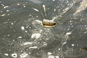 A discarded plastic bottle pollutes a river that is source of drinking water for a city.
