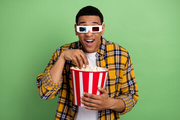 Photo of astonished positive person watch movie 3d glasses eat popcorn isolated on green color background