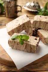 Tasty chocolate halva with mint on wooden table
