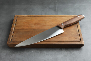 Knife and wooden board on grey textured table
