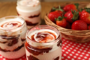 Tasty yoghurt with jam and strawberries on table, closeup