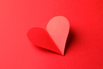 One bright paper heart on red background