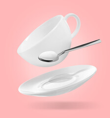 Spoon, cup and saucer falling on pink background
