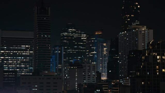 Nighttime cityscape of Bangkok showing illuminated buildings and skyscrapers against a dark sky.