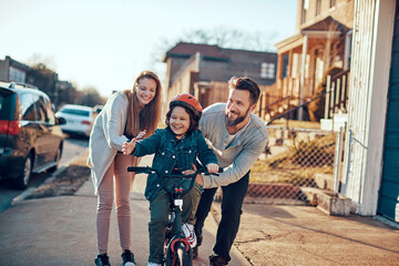 Boy learning to ride a bike with supportive parents