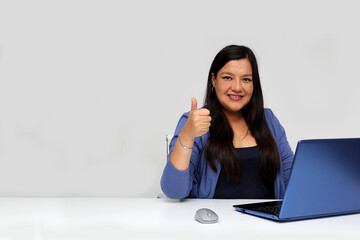 Latina 40 year old woman works with her laptop in office and likes with her hand and points to the copy space for promotions and discounts