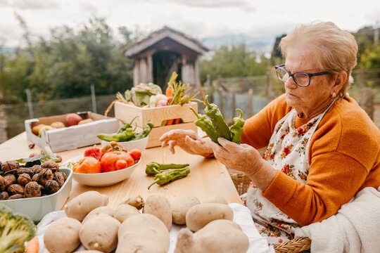 Elderly woman sorting fresh vegetables at table