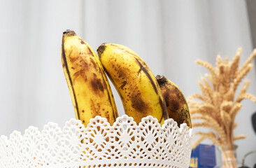 Ripe bananas in a white basket in the kitchen.
