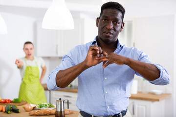 Frustrated man removing wedding ring from finger on background of angry wife
