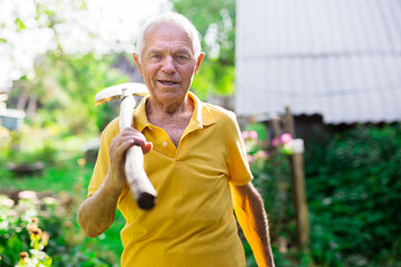 Portrait of an elderly man with shovel in garden