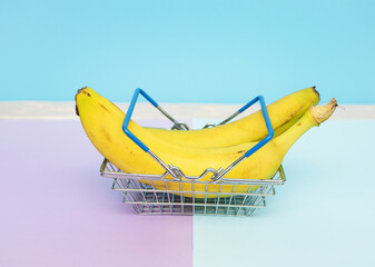 Bananas in a supermarket trolley on a plain background. Creative picture with bans in a grocery...