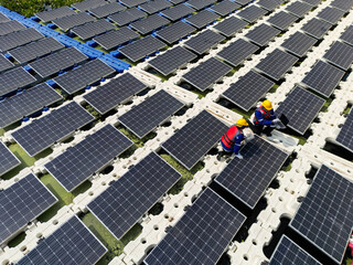 Top aerial of Photovoltaic engineers work on floating photovoltaics. workers Inspect and repair the solar panel equipment floating on water. Engineer working setup Floating solar panels on lake.