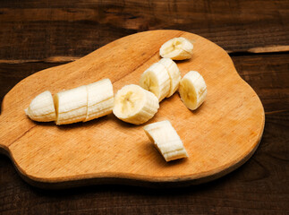 Appetizing sliced ​​banana on a kitchen cutting board, top view. Banana without peel.