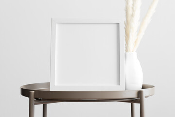 White square frame mockup with a pampas decoration on the beige table.