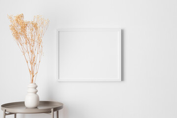 White frame mockup on the wall with a gypsophila decoration.
