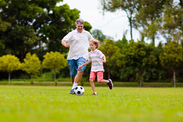 Father and son play football. Dad and kid run.