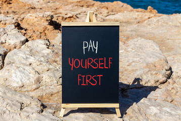 Pay yourself first symbol. Concept words Pay yourself first on beautiful black chalk blackboard. Beautiful red stone blue sea background. Business and pay yourself first concept. Copy space.
