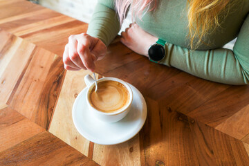 Close-up of a hand stirring a coffee.