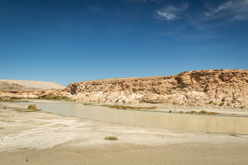 Muddy shallow stream running through the high plains desert landscape with blue sky in Wyoming, USA 