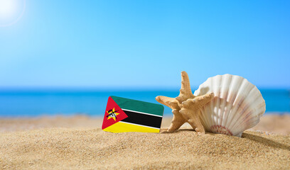 Tropical beach with seashells and Mozambique flag. The concept of a paradise vacation on the...