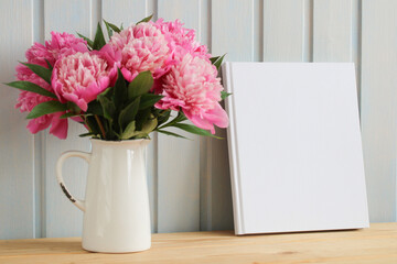 book with an empty white cover and a vase for flowers. mockup album, copy space. the creator of summer scene in cottage.