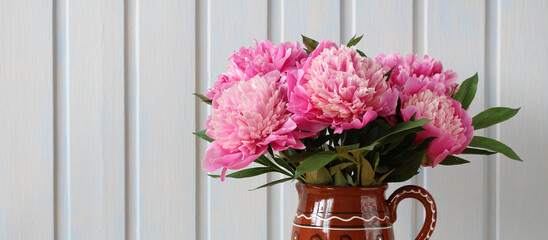 bouquet of peonies in a clay jug against a white board wall. garden flowers. Summer is a concept phone. cottage core.