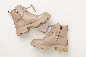 Beige trendy boots on concrete background, top view.