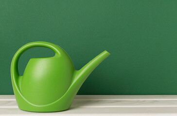 Green watering can on wooden table