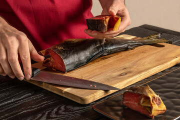 Smoked humpback salmon. Process of cutting sea fish. Oncorhynchus gorbuscha. Close-up of hands...